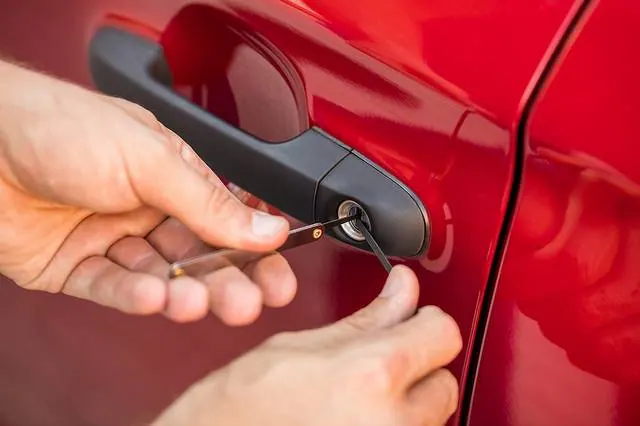 Person using a lock pick tool on a car door lock, demonstrating locksmith services for emergency lockout assistance.