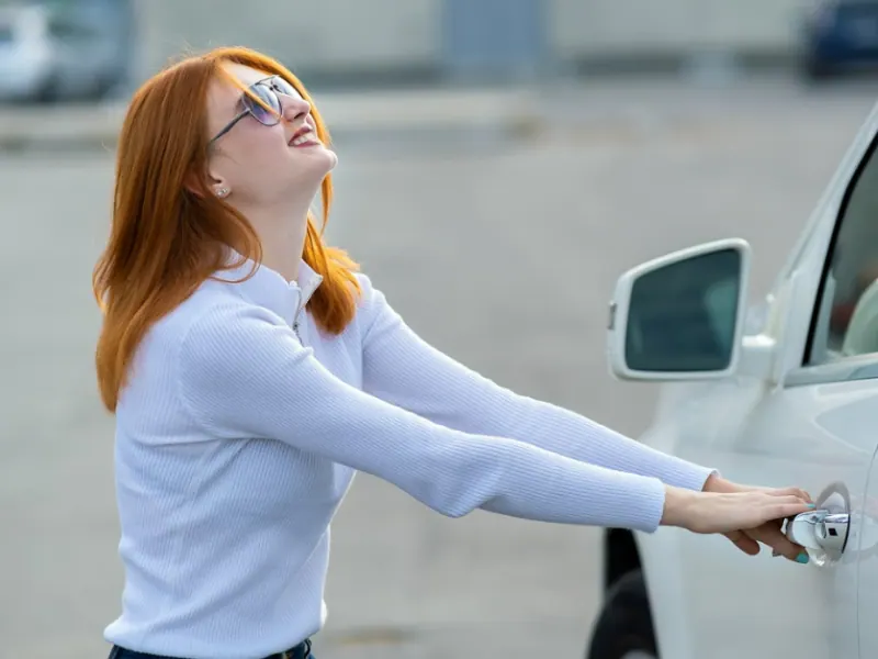 Woman attempting to open a car door, illustrating automotive locksmith services for car lockouts.