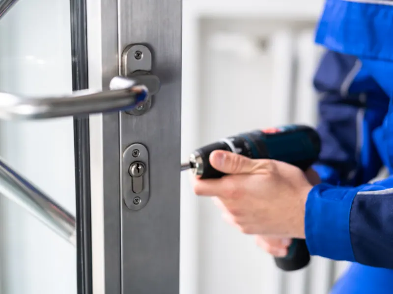 Professional locksmith installing a commercial door lock with a power drill, emphasizing security solutions for businesses.