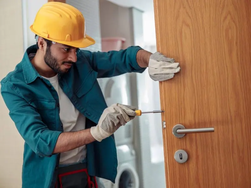 Locksmith in uniform installing a door knob, showcasing professional service and expertise in enhancing security.